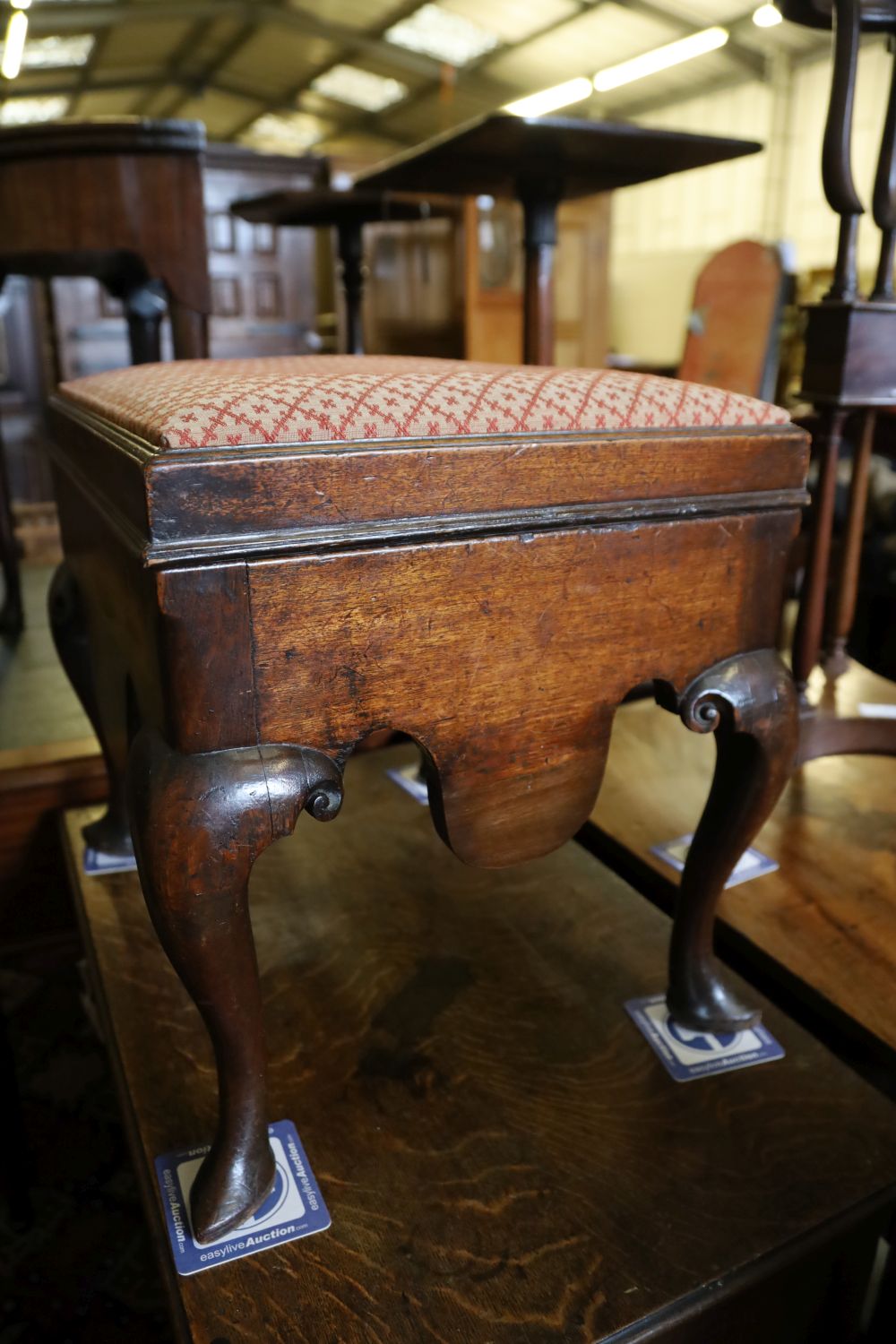 A George III mahogany box stool, the hinged lid with upholstered top above shaped apron and cabriole knees, on pointed pad feet, width
